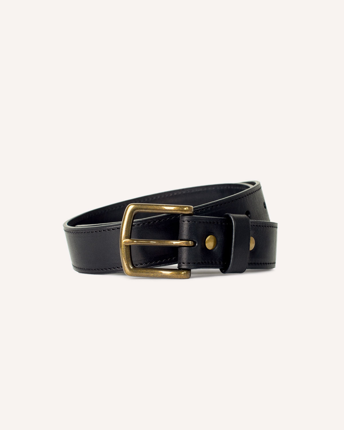 An Heirloom Belt from Archive Leather Goods, in Black Horween Dublin leather with a solid antiqued brass buckle; coiled.