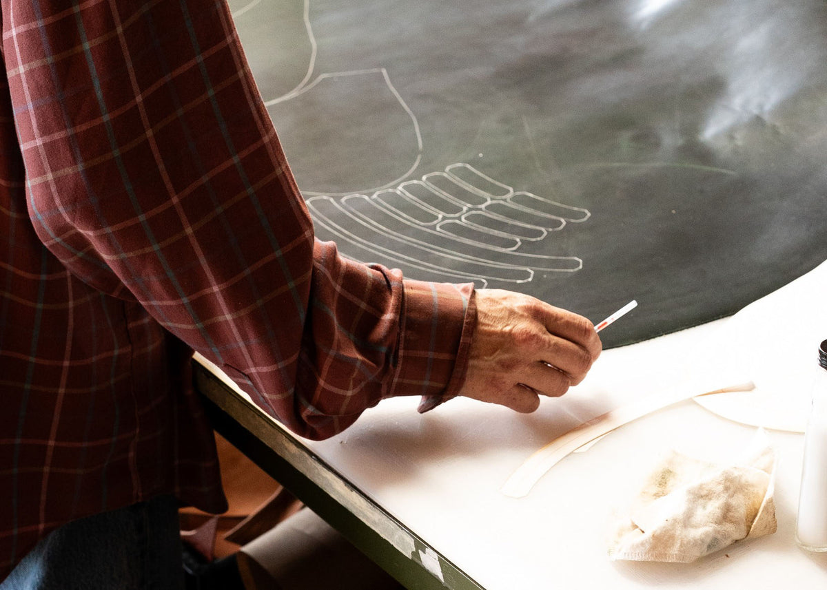 A hand drawing a boot pattern on paper.