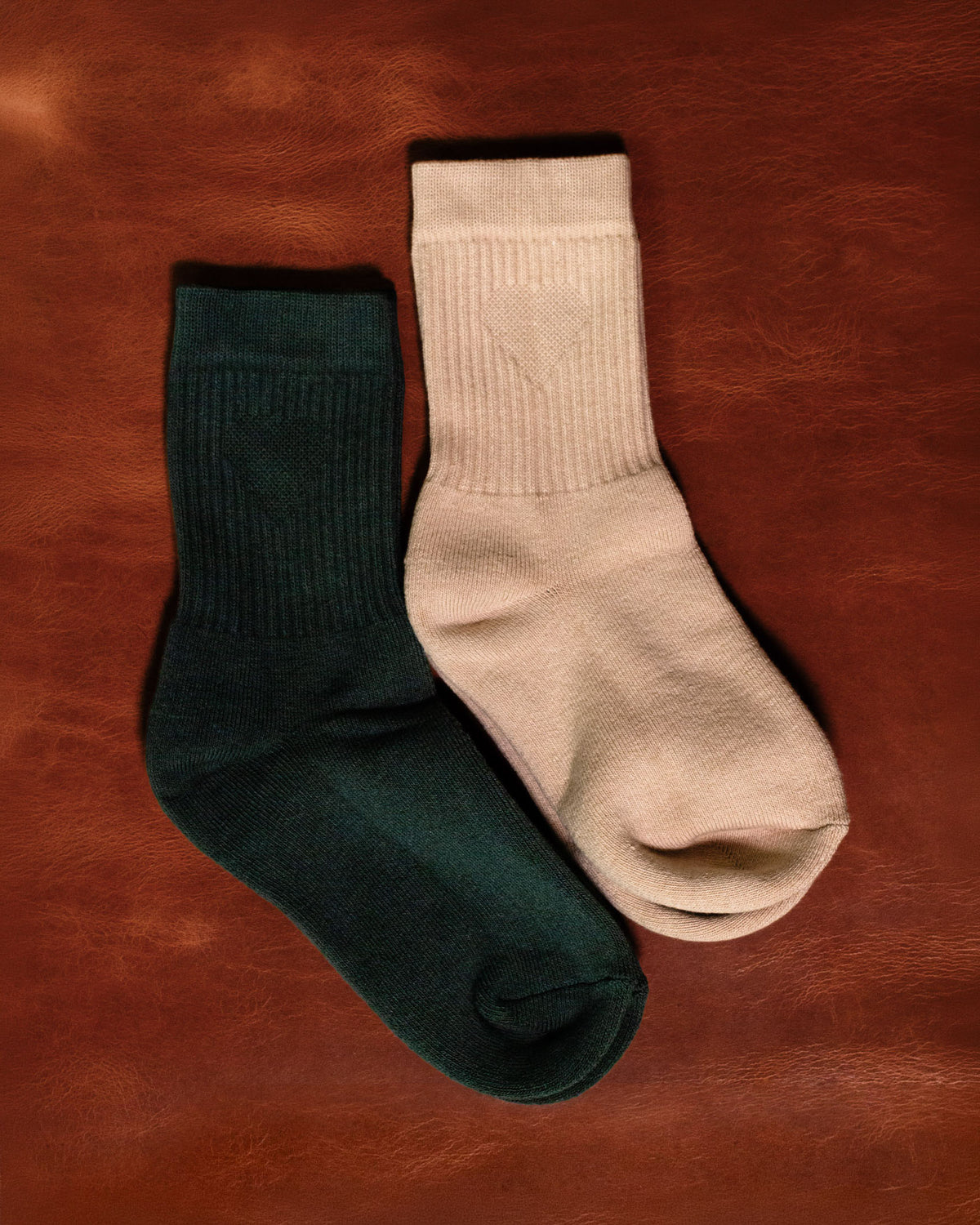 Foundation Socks from Archive Leather Goods in Driftwood (natural) and Salal (green) on a leather background.