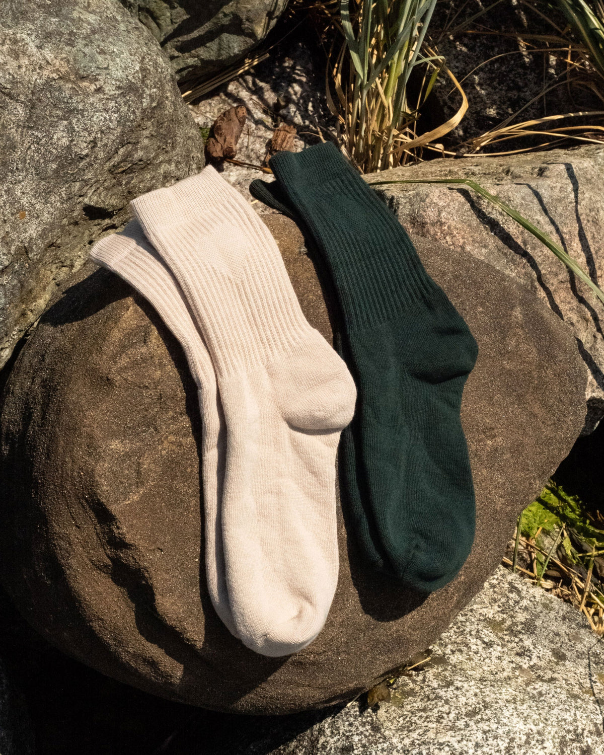 Foundation Socks from Archive Leather Goods in Driftwood and Salal, draped over a rock.