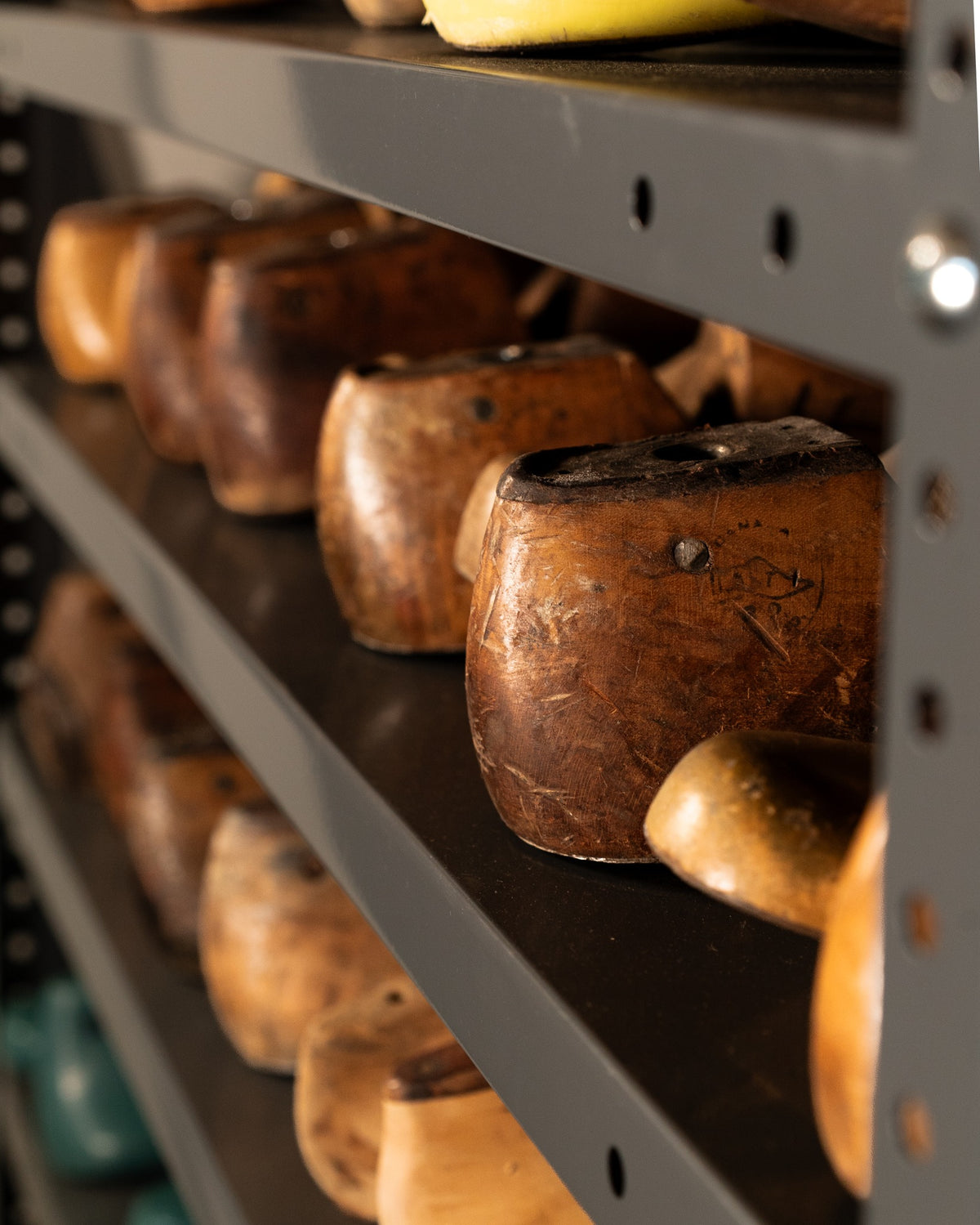 Wooden shoe lasts on metal shelves in the workshop.