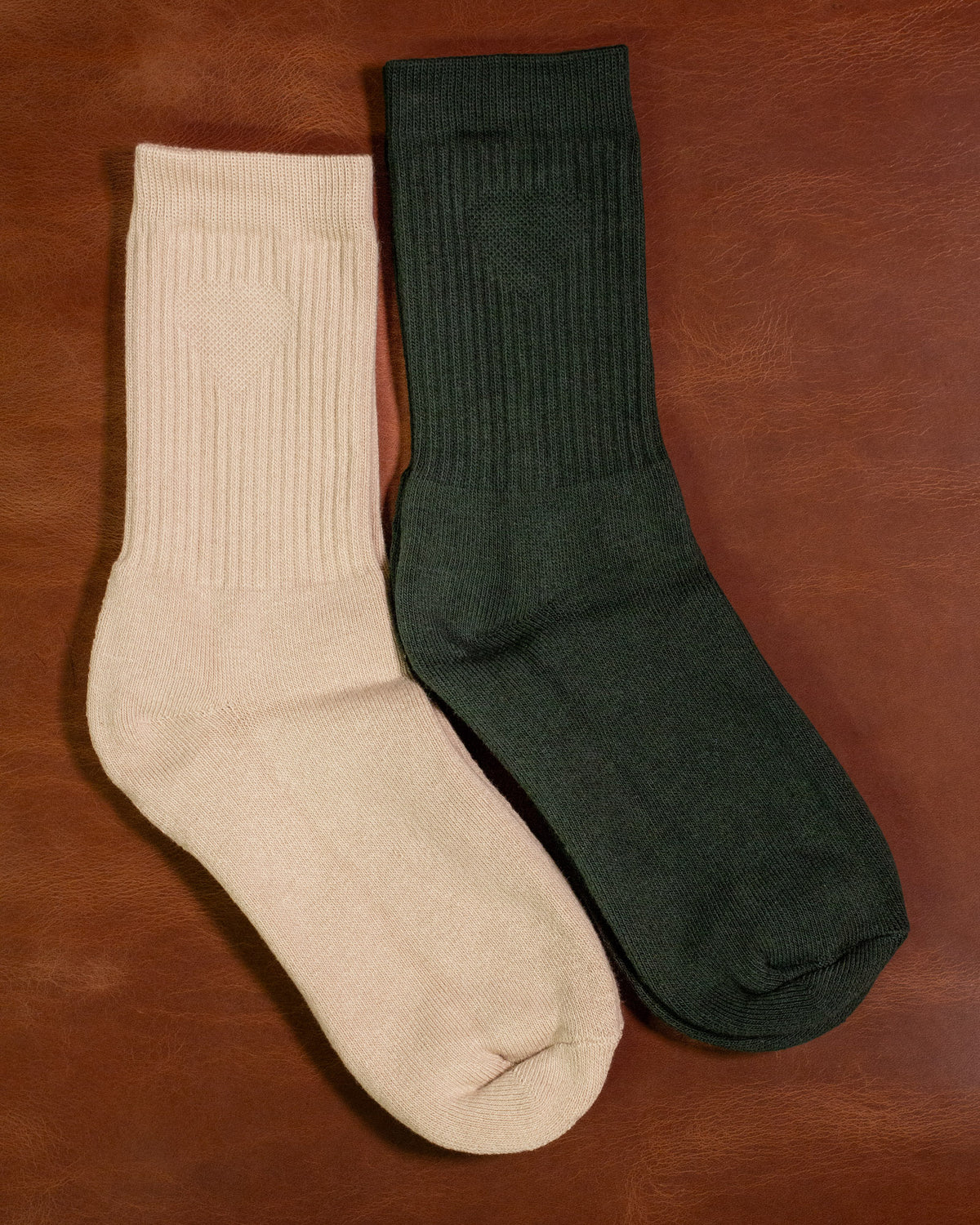 Foundation Socks from Archive Leather Goods in Driftwood (natural) and Salal (green) on a leather background.